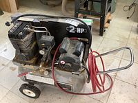 Overview of compressor showing tank, motor, wheels, handle and hose