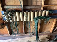 Green coated metal garden spikes, some bundled and inserted into cardboard tubes mounted on the wall.