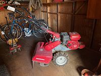 Side view of entire rotary tiller showing handlebars, wheels, tines and engine