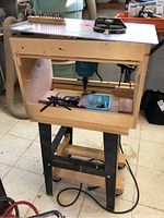 Full view of router table assembly with Makita router installed on wooden table and black stand beneath