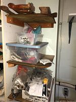 Tools and hardware on wooden shelves including bins, bags, and assorted parts.