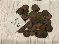 Top-down view of approximately 50 circulated one penny bank tokens from the Bank of Upper Canada and other pre-Confederation Canadian banks spread on a white cloth.
