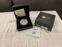 Open velvet case with coin in capsule next to presentation box