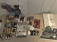 Wide overview of assorted collectibles including comics, cards, pins, and a large stack of cards.