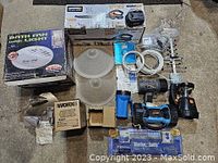 Lot of mixed home maintenance items and lighting products including boxed bathroom fan light, ceiling light covers, flashlights, and Bluebox Buddy visible.