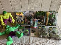 Full view of the lot showing various Hulk collectibles including figures and plush toy arranged on a table.