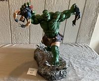 Front view showing Hulk lifting Wolverine by each hand above rocky base