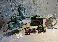 Full lot showing two green patina metal horse statues, John Deere lunchbox, toy tractors and John Deere beer stein