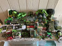 Lot overview showing assortment of Hulk toys and collectibles laid out on table