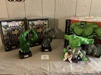 Front view showing green and gray Hulk busts with original boxes plus larger Hulk/Bruce Banner statue with colorful box