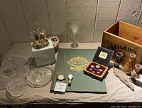 Full lot overview showing wooden crate, local atlas, pocket watch, wristwatch, coin set, crystal bowls and dishes, glass cake stand, wood decor, and Cherished Teddies boxed collectible figures.