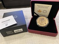 Photo showing the coin in a protective clear clamshell inside a red presentation box, along with the black retail box and a MaxSold tag.