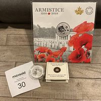 2018 WWI Armistice coin in original packaging with poppy design and cemetery background, showing the coin face with soldier design.