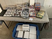 Overview of binder, plastic tub, sealed display boxes and blue tub on table