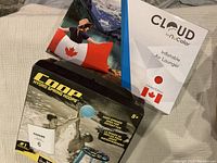 Photo of Cloud by NuColor Inflatable Air Lounger with Canadian Flag design box and Hydro Spring Hoop water sports game box on carpet near sofa.