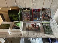 Full view of the lot showing Hulk bust box, Lady Death action figure, Spiderman figures, Thor action figure, and Green Lantern figure on table.