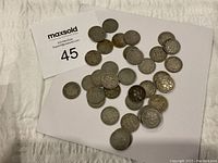 Overhead view of entire lot spread on white background, showing mixed obverse and reverse sides of coins.