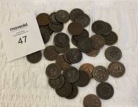 Top-down group shot of approximately 37 large cents on white cloth with lot card