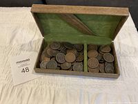 Wooden hinged box open showing two compartments filled with large cents on a white cloth.