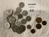 Overall collection of 14 coins including mostly Kennedy half dollars, 3 quarters, a Lincoln penny, and 5 tokens of various sizes and colors, laid out with MaxSold label number 44.