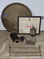 Photo of six lot items arranged including brass tray, framed proclamation, balance scale, candelabra, rack, and lamp as viewed from front