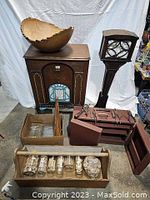 Overview showing bread bowl on top of the vintage radio cabinet, antique speaker stand to the right, wooden tool shelf and toolbox, jars and boxes with parts on floor