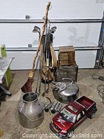 Photo showing vintage golf clubs and bag with shafts exhibiting corrosion, a handmade corn broom, stainless steel milker with parts and jug, and a red remote control Ford F-1 Traxter X9 racing truck without controller.