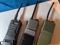Front view of three walkie talkies with antennas and carrying straps