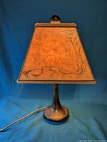 Front view of the Art Nouveau table lamp with trapezoidal shade and floral design.