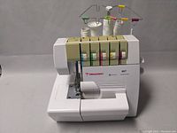 Front and right side view of Dragonfly 857 sewing machine with five thread spools, color-coded tension dials, and branding.