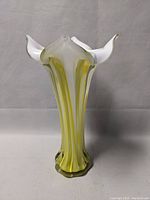 Front view of tall hand blown glass vase in white and yellow with flared petal-shaped top.