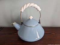 Light blue enamel kettle with twisted cream handle and lid, closed.