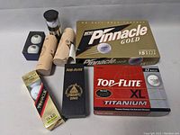 Overview of various golf ball boxes and sleeves including Pinnacle Gold and Top-Flite XL Titanium, plus branded golf ball tubes and a commemorative box.