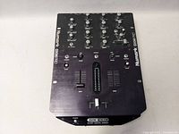 Top view of Numark DXM Pro DJ mixer showing knobs, faders, and buttons for channel control and audio mixing.