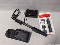 Argus camera, mini tripod, selfie stick with pouch all displayed on gray surface