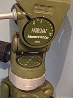Close-up of Manfrotto 141RCNAT model indicator on olive green tripod head showing precise angle markings.