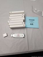 Photo showing 8 individual white USB flash drive boxes stacked and one USB flash drive with the cap removed placed beside them. The USB drive has company branding in red and black on white plastic.