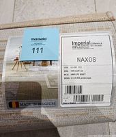 Close-up of carpet label showing brand Naxos, dimensions 160x230 cm, pile 100% PF HSET, made in Belgium.
