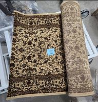 Rolled and partially unrolled carpet runner showing the light brown floral patterned design and border accents.