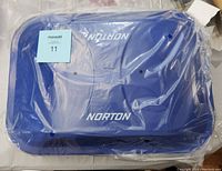 Top view of blue Norton branded BBQ grill with lid, brand name visible through sealed plastic wrapping.