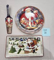 Front view of all pieces showing Christmas Santa Claus designs on tray, plate, and utensil.