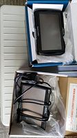 Two Magellan RoadMate GPS units in original boxes on a white table, one includes power cable and mounting accessories