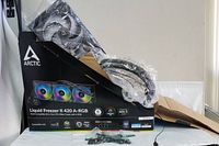 Arctic Liquid Freezer II 420 A-RGB cooling unit partially unpacked showing fans and radiator with packaging in the background.