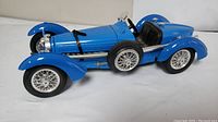 Side view of blue diecast Bugatti 59 model showing detailed bodywork and spare tire.