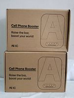 Two closed brown cardboard boxes labeled 'Cell Phone Booster' with branding and slogan visible