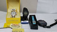 Full lot showing Invicta watch box with watch and paperwork, Casio G-Shock watch, black stopwatch, and Avon watch in box.