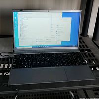 Opened laptop powered on showing Windows 10 desktop and device manager window with visible keyboard and screen.
