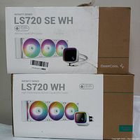 Two boxed DeepCool 360mm liquid CPU coolers, LS720 WH and LS720 SE WH models, packaging slightly distressed.
