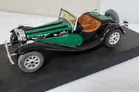 Side view of the Bugatti 55 DeLaChapelle model car showing green and black paint with detailed engine and interior visible.