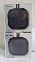 Two unopened Omthing Outdoor BT Speaker boxes stacked, front view showing product image and branding